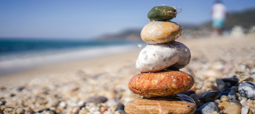 coloured stones stacked on top of each other on a beach to show the tranquillity of a Cornish yoga retreat next to the ocean